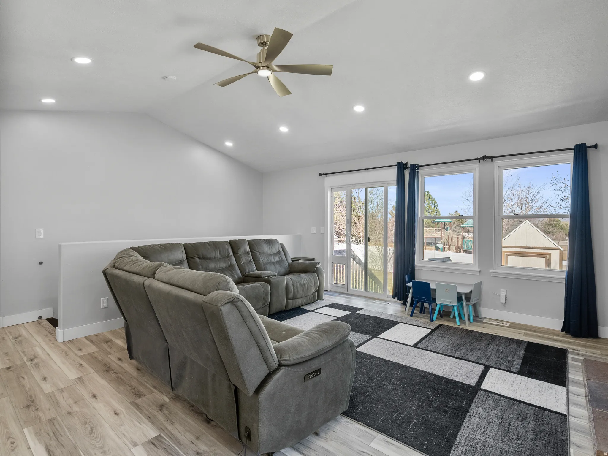 Living room with light wood-type flooring, recessed lighting, a ceiling fan, and vaulted ceiling