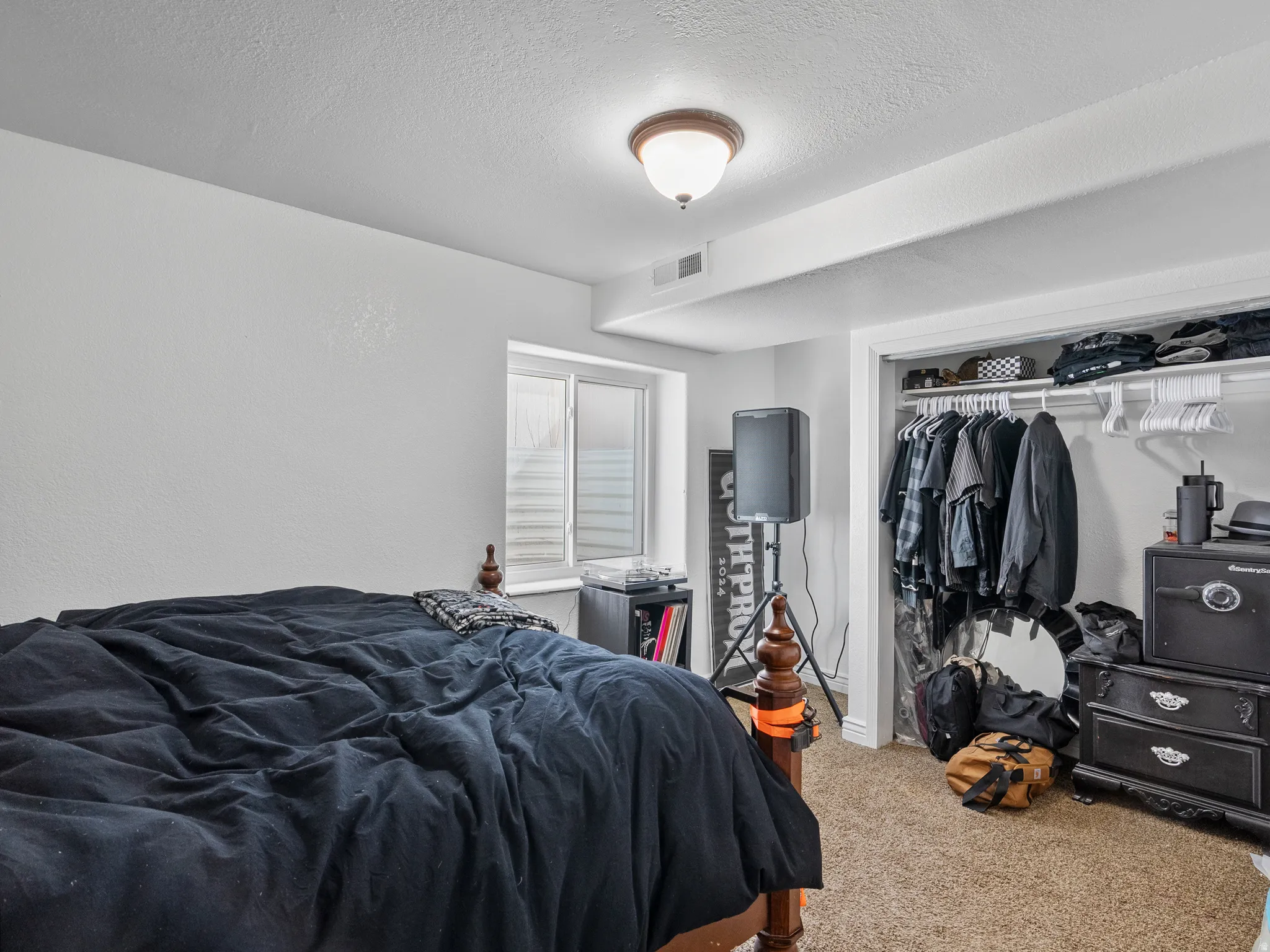 Bedroom with light carpet, a closet, and a textured ceiling