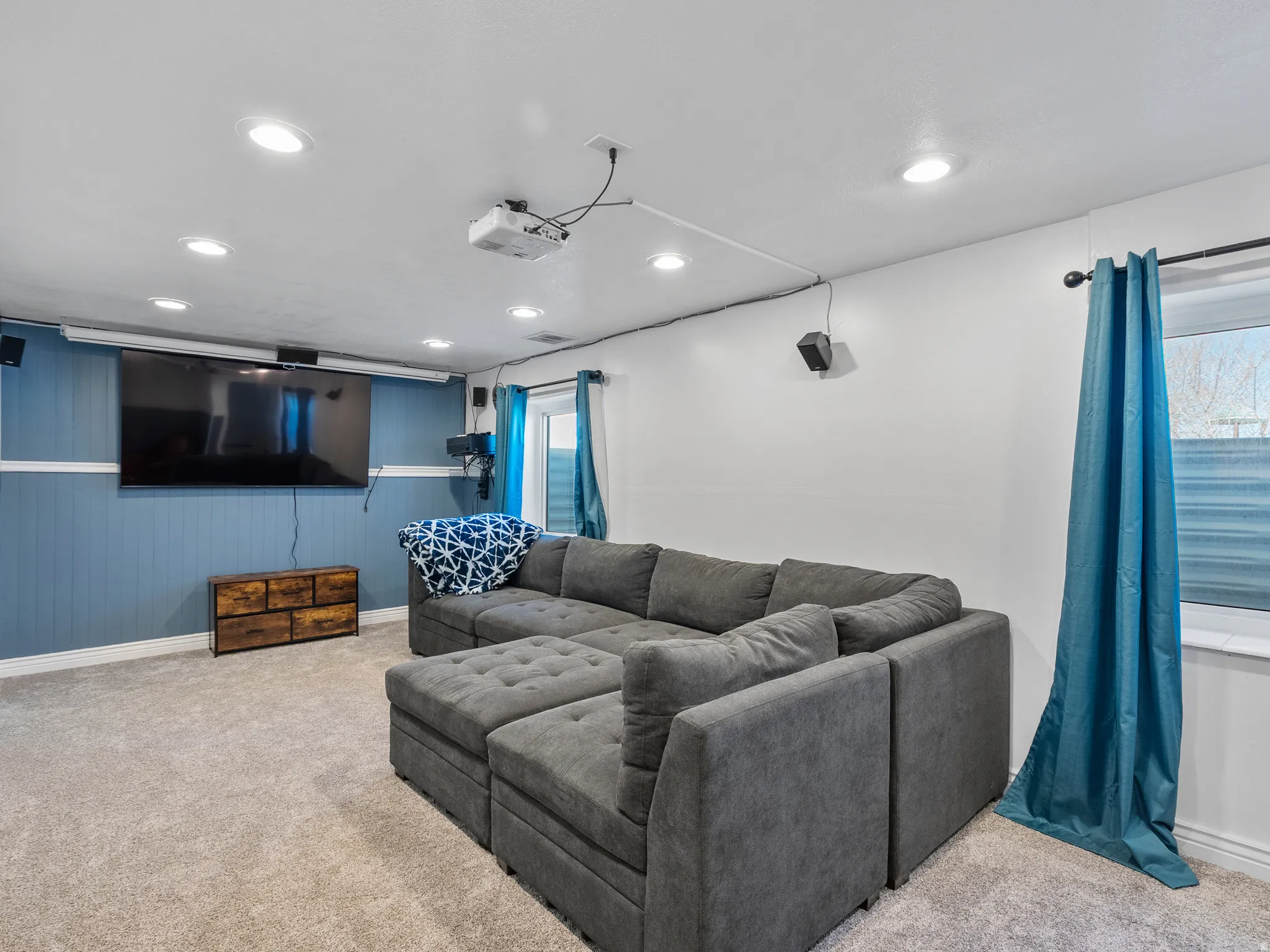 Carpeted living room with recessed lighting and wood walls