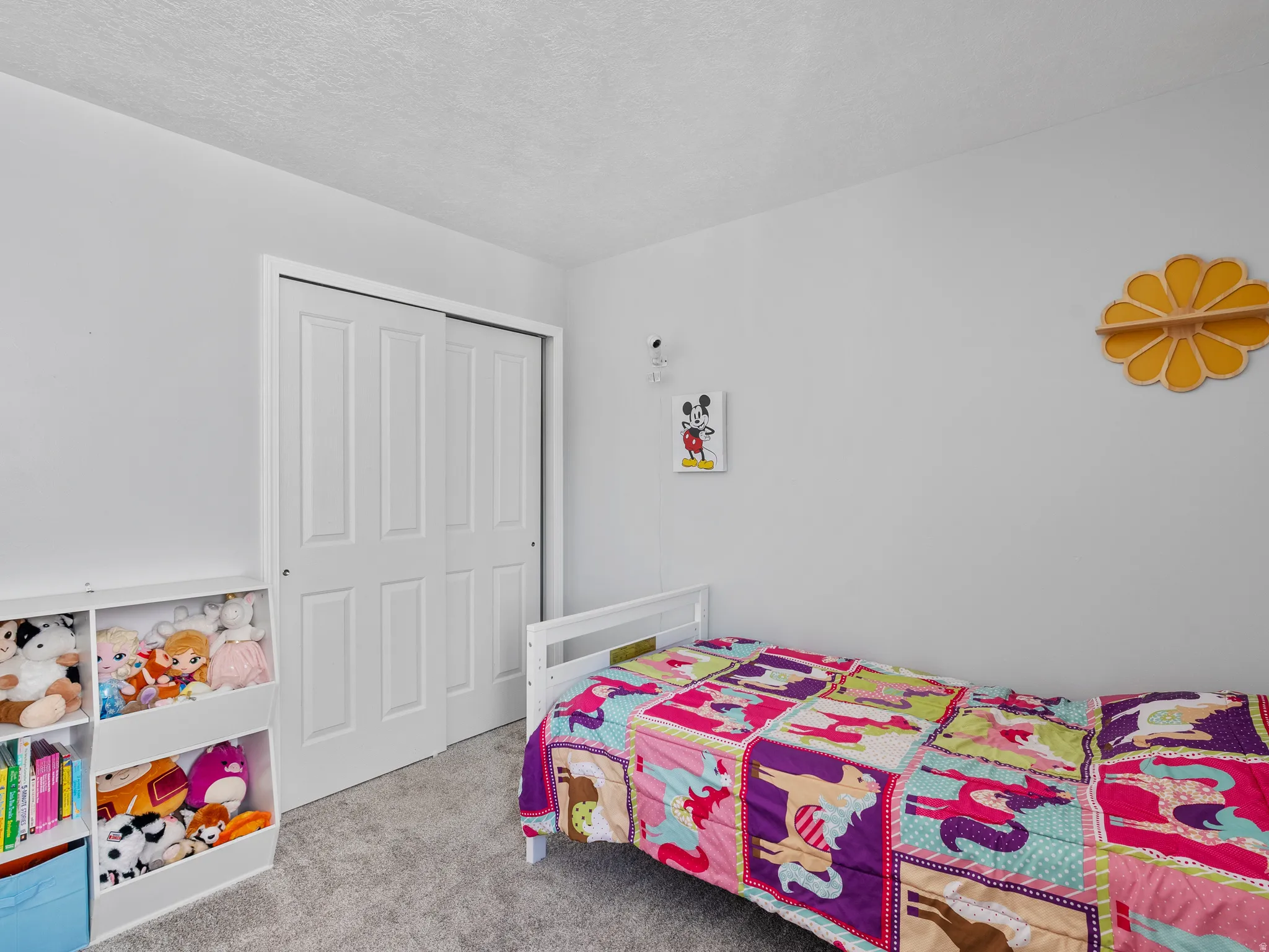 Bedroom with light colored carpet, a closet, and a textured ceiling