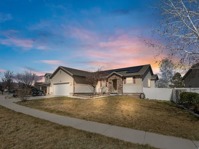 Ranch-style house with solar panels, an attached garage, stone siding, and concrete driveway