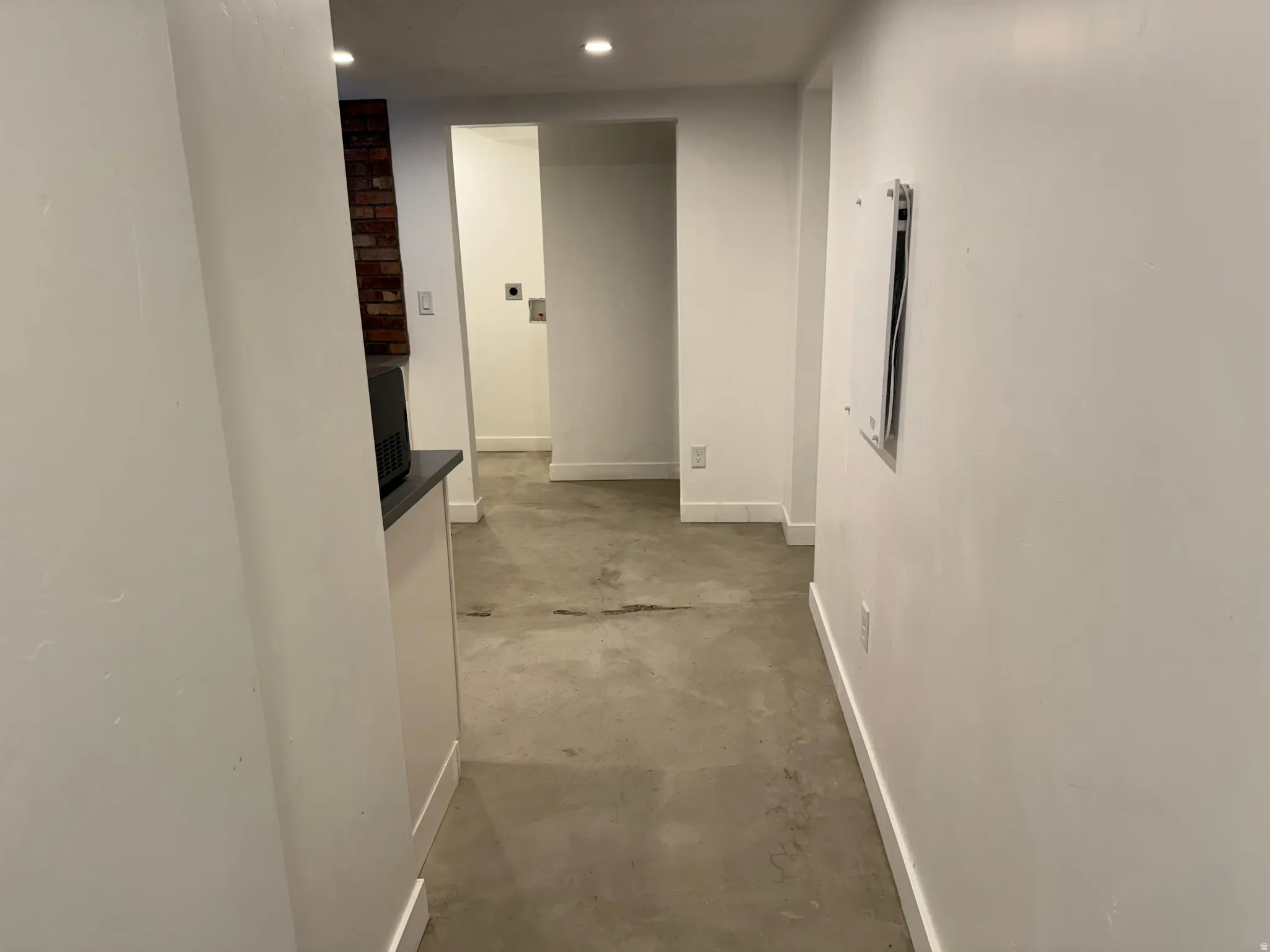 Hall featuring unfinished concrete flooring, recessed lighting, and electric panel
