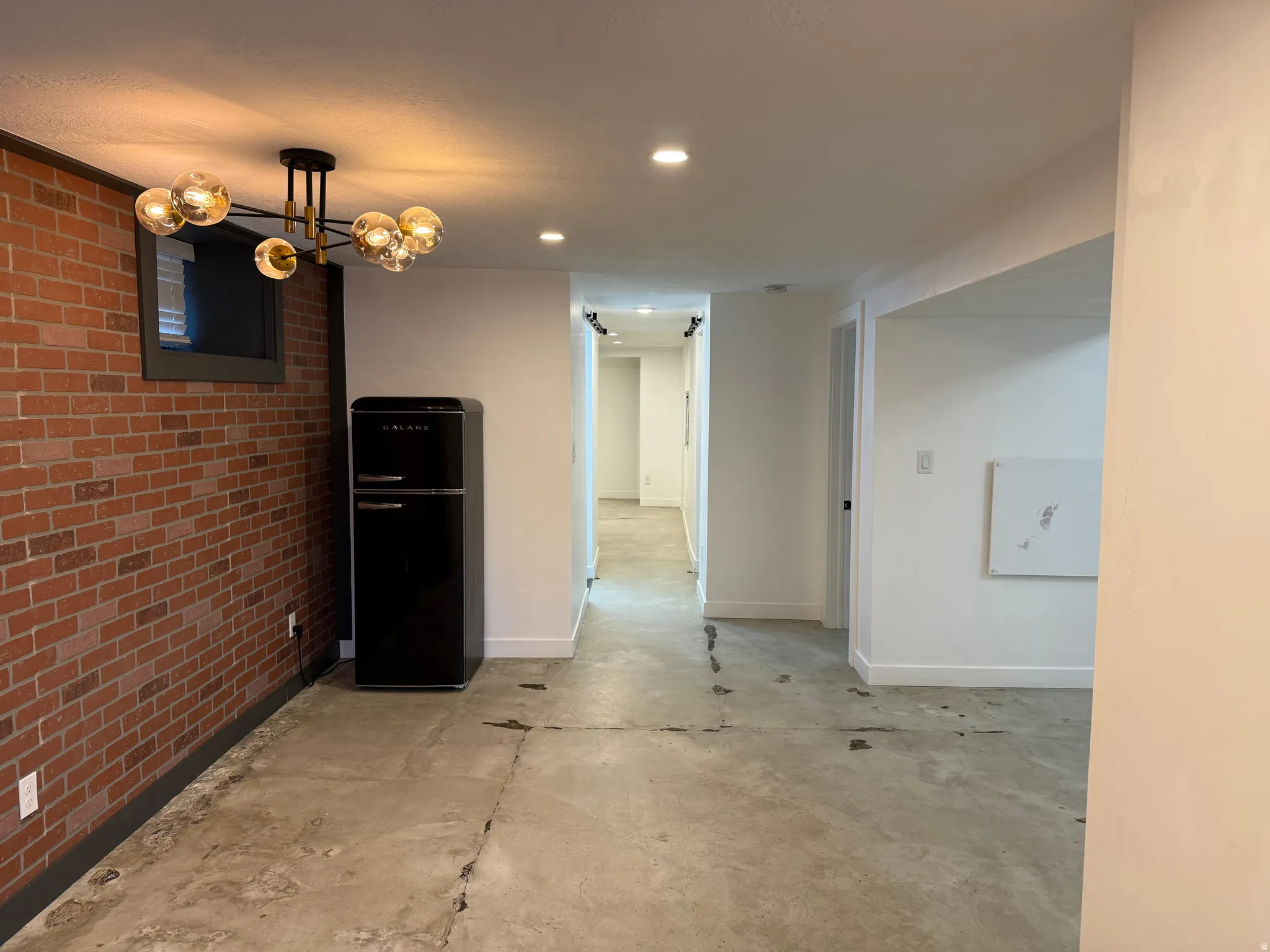 Unfurnished dining area with brick wall, unfinished concrete flooring, and recessed lighting