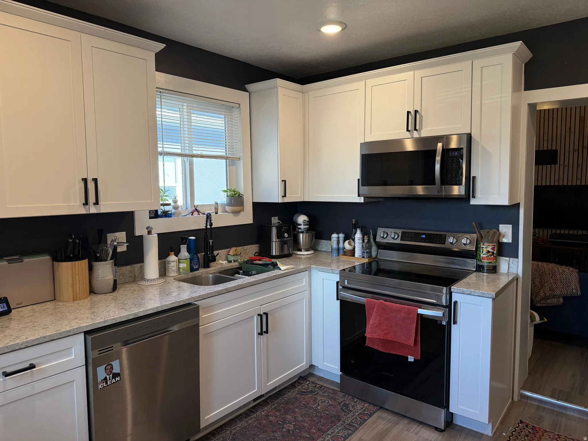 Kitchen with stainless steel appliances, white cabinets, light stone counters, dark wood finished floors, and recessed lighting