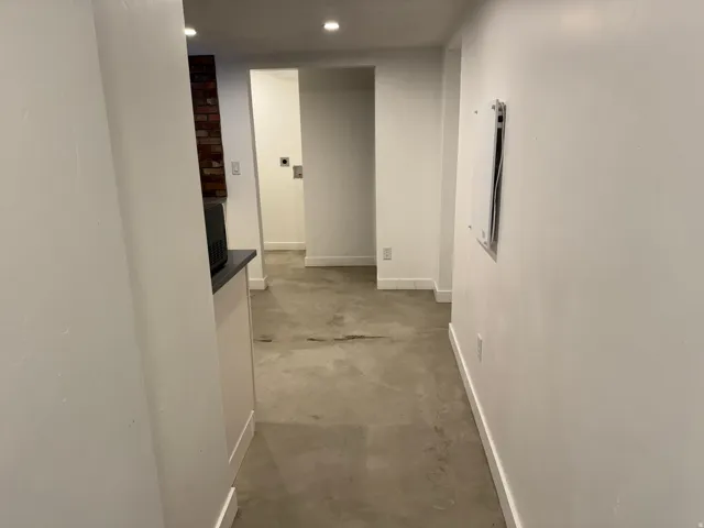 Hall featuring unfinished concrete flooring, recessed lighting, and electric panel