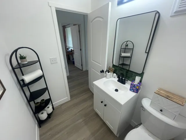 Half bathroom featuring vanity, dark wood-style flooring, and backsplash
