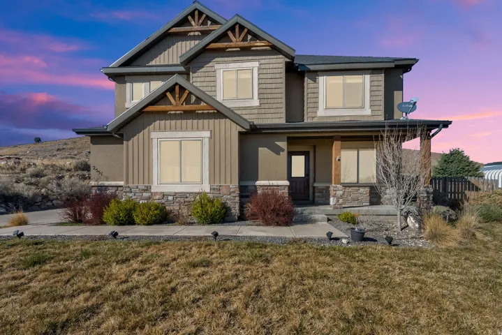 Craftsman inspired home with covered porch, a front yard, and stone siding