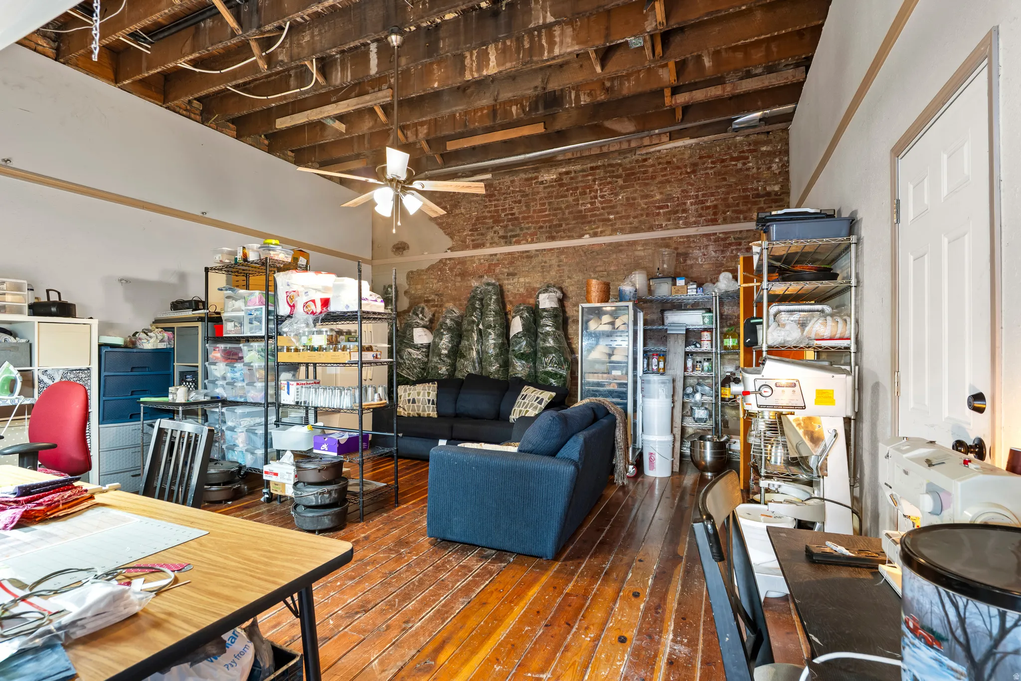 Main floor. Work area with brick wall, ceiling fan, and hardwood / wood-style flooring