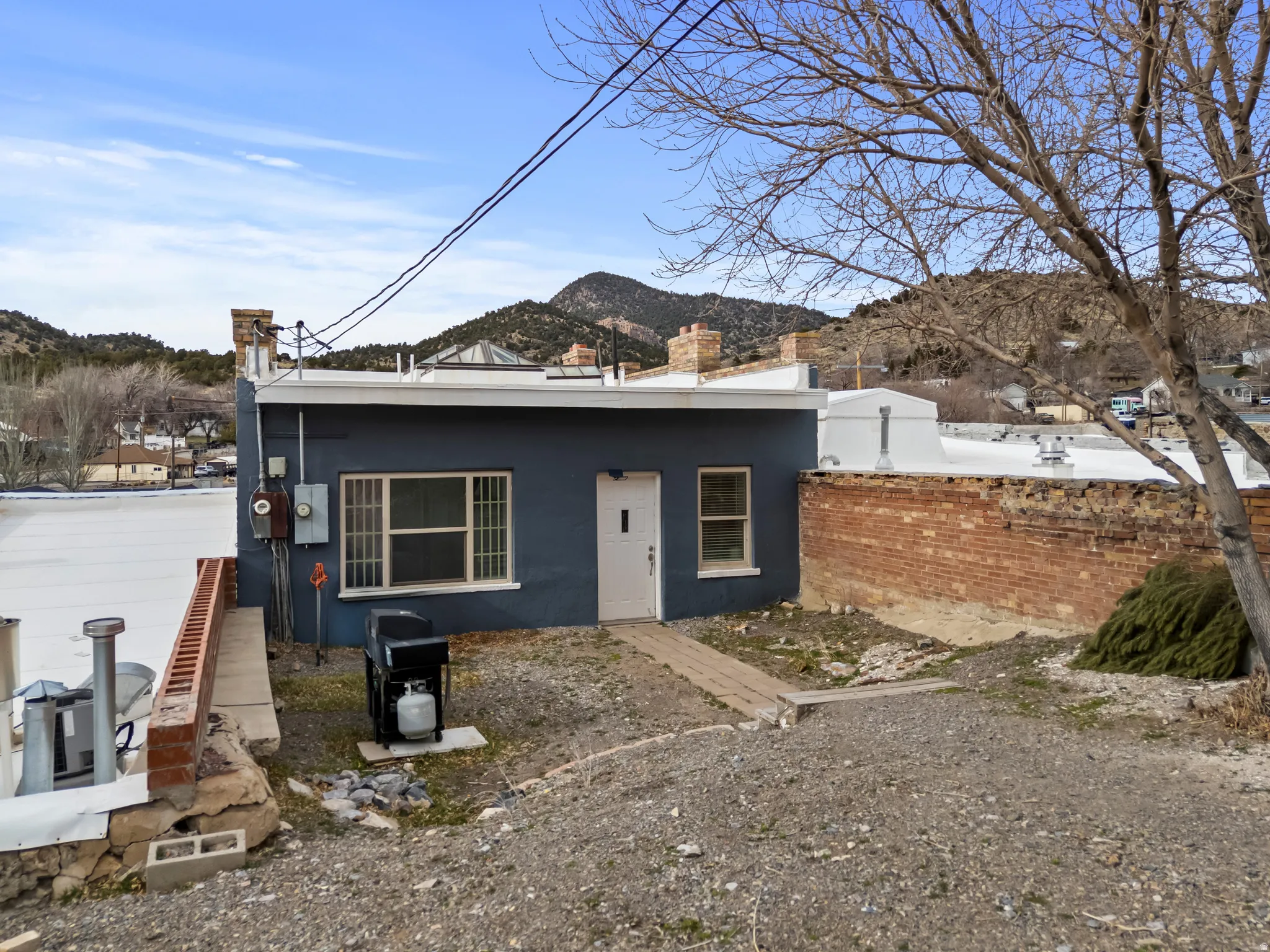 Apartment entrance - south side of building. View of front facade featuring a mountain view, a chimney, and stucco siding