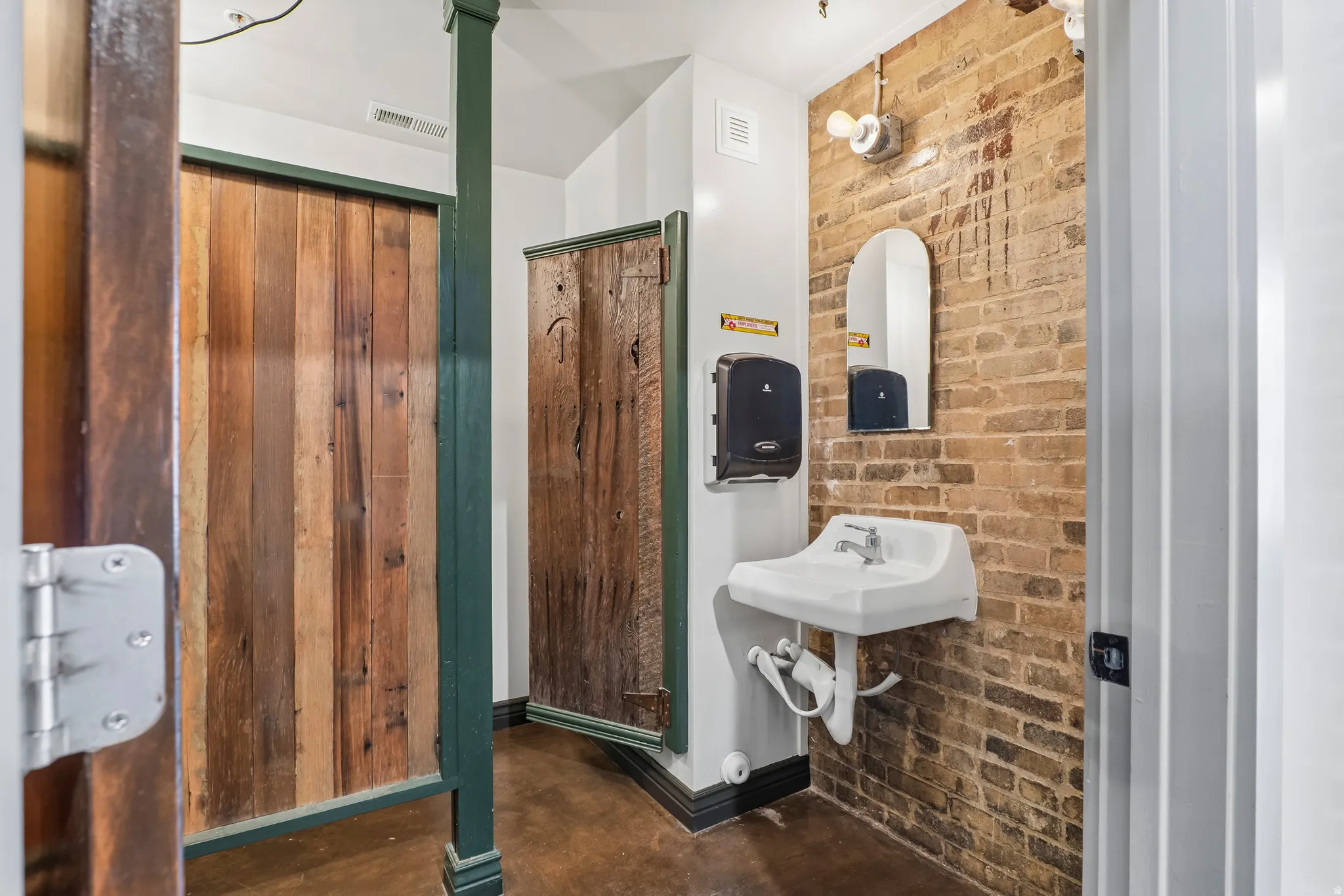 Half bath featuring brick wall