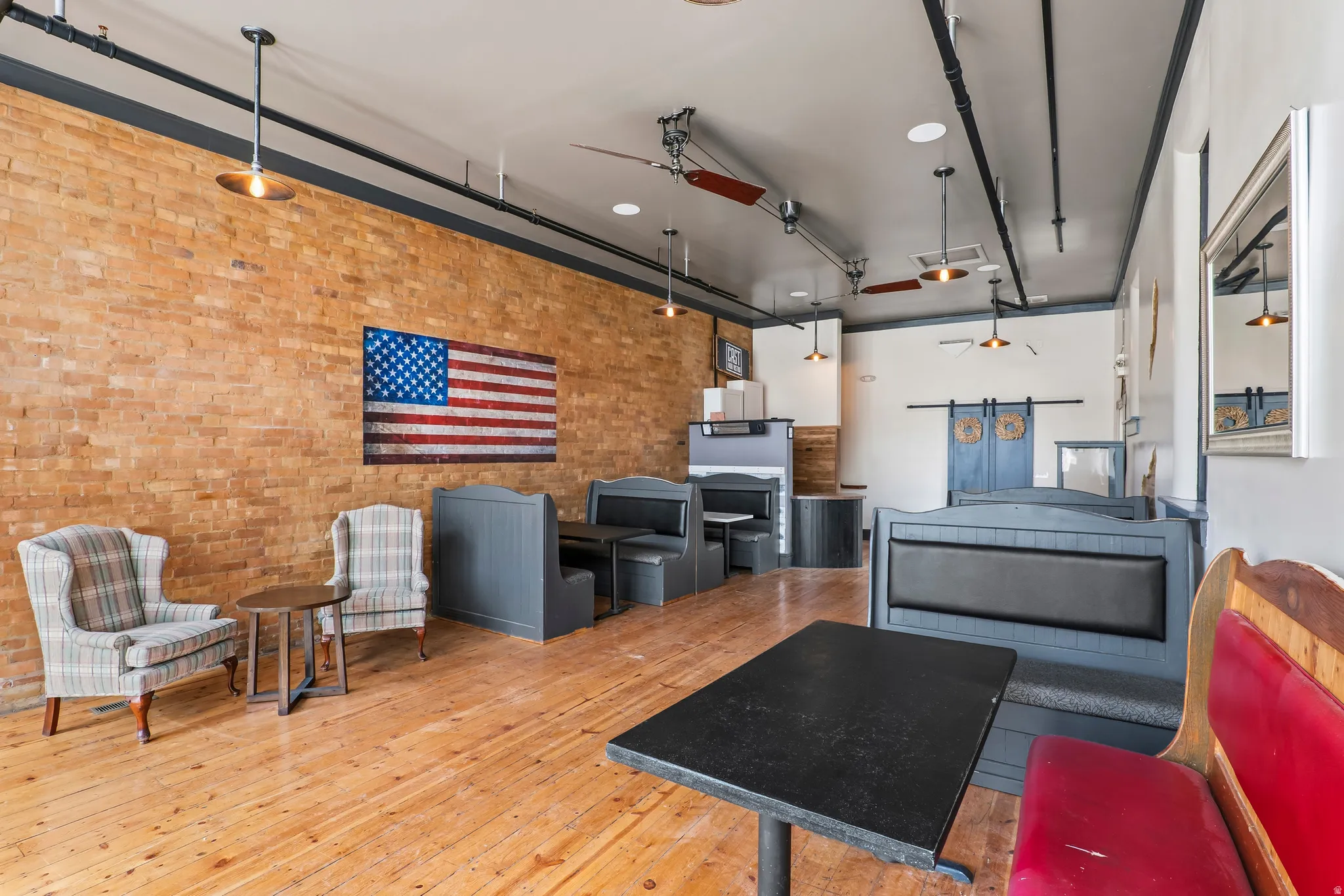 Living area featuring wood-type flooring, ceiling fan, and brick wall