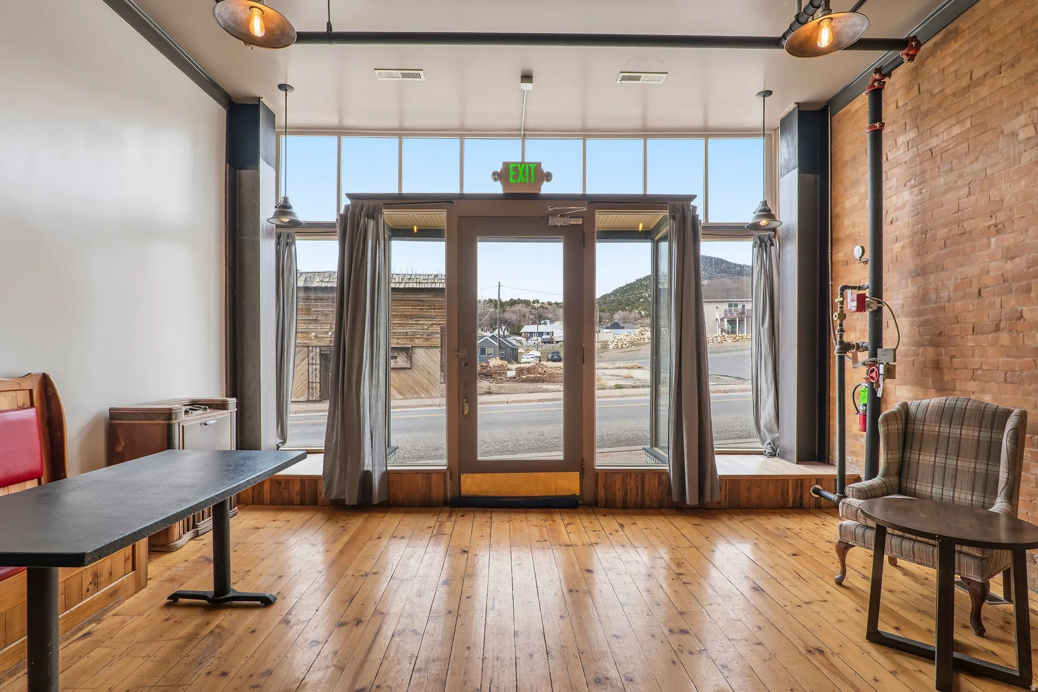 Doorway to outside featuring wood-type flooring, floor to ceiling windows, a mountain view, and brick wall