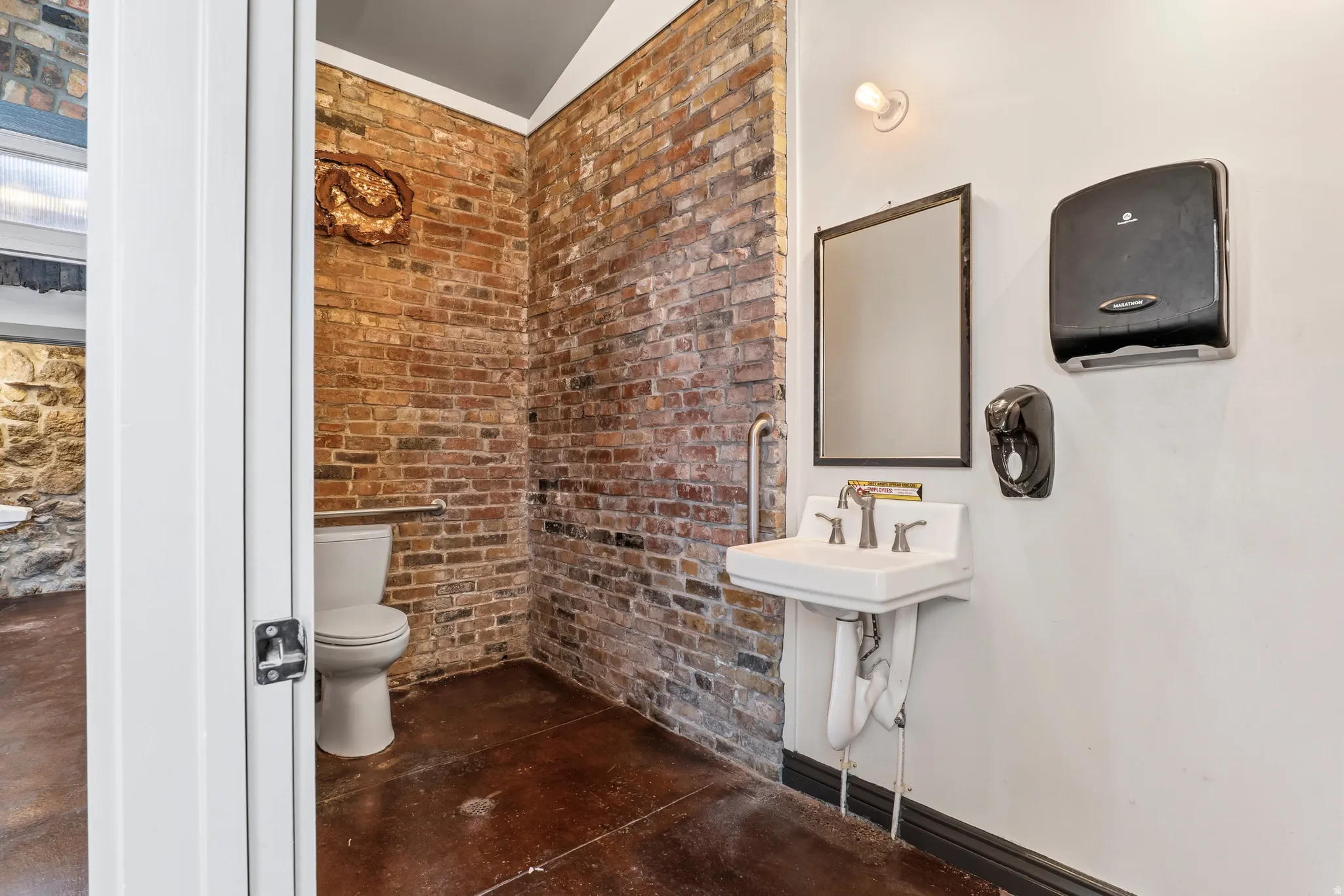Half bath featuring brick wall and finished concrete flooring