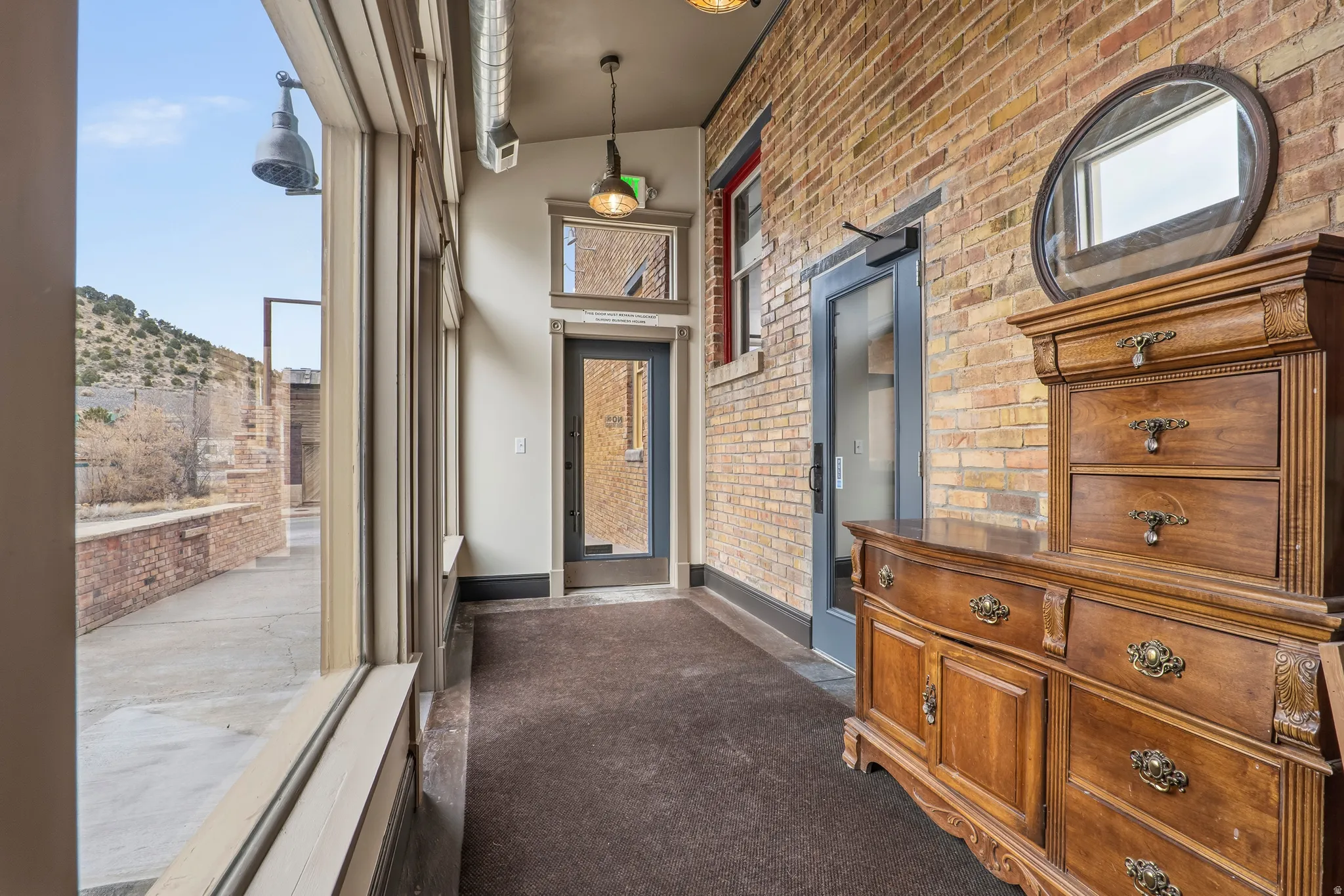 Corridor with brick wall, a high ceiling, dark carpet, and a mountain view