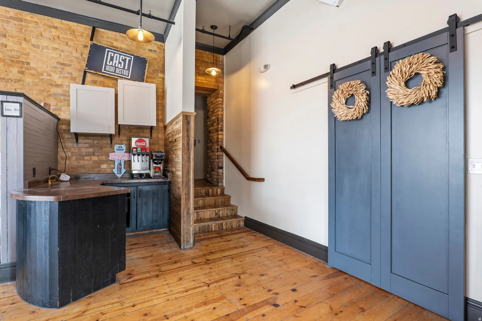 Bar area featuring brick wall, a barn door, butcher block countertops, and white cabinets