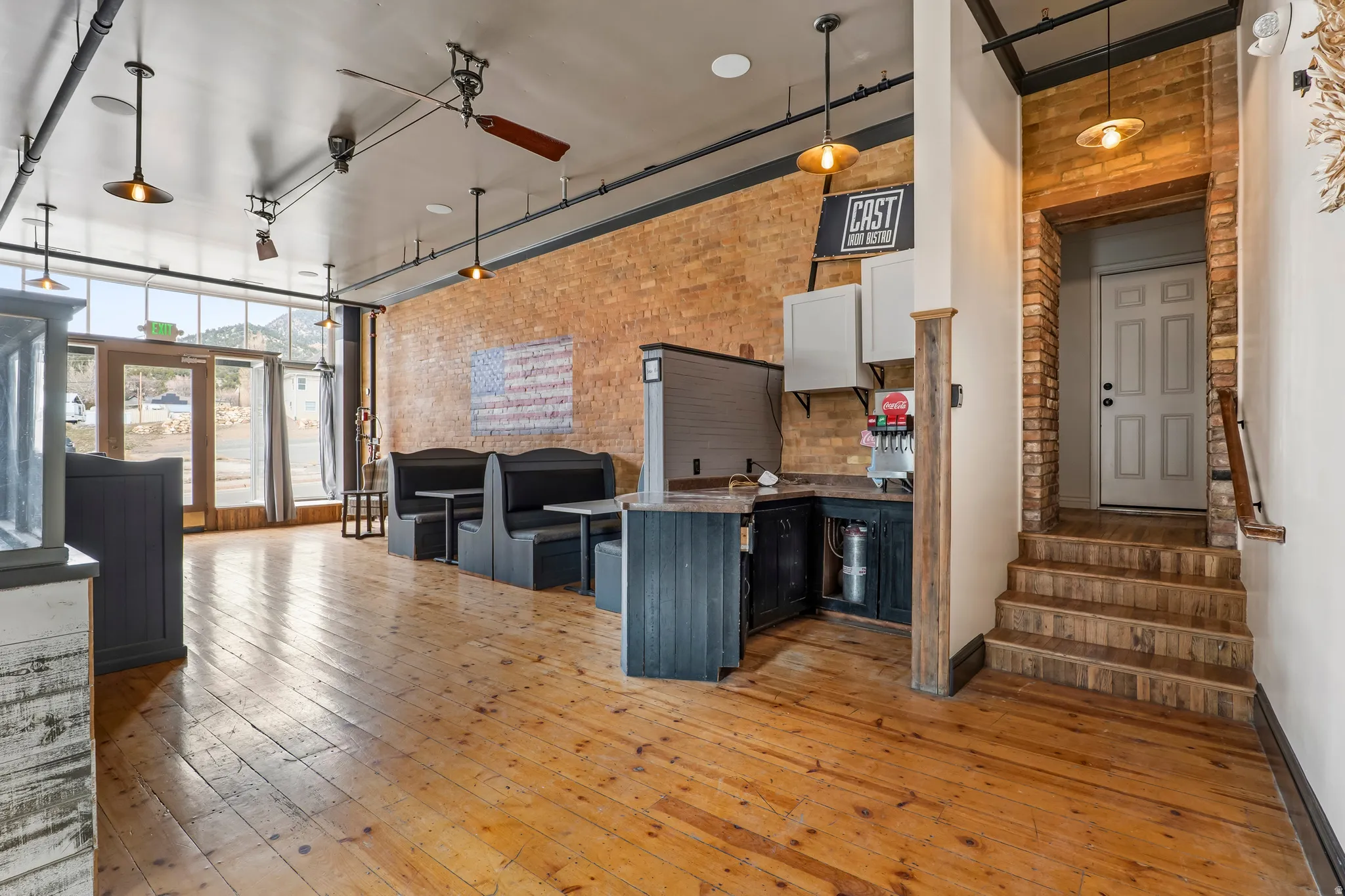 Kitchen with brick wall, a high ceiling, a breakfast bar area, a peninsula, and dark countertops