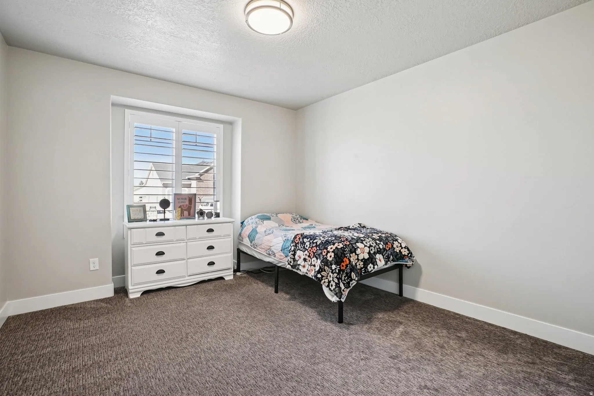 Bedroom featuring dark colored carpet and a textured ceiling