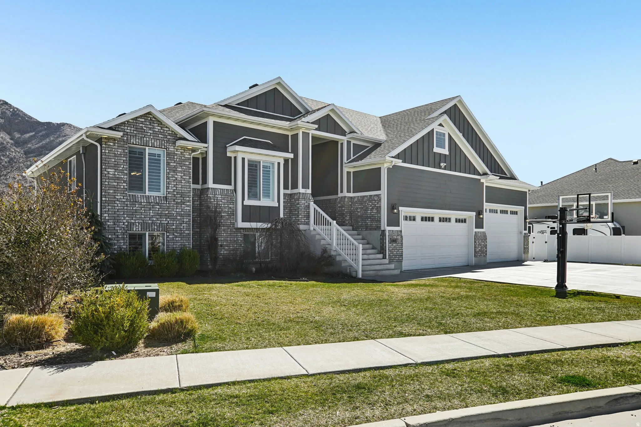 Craftsman-style house featuring board and batten siding, brick siding, a front lawn, and concrete driveway