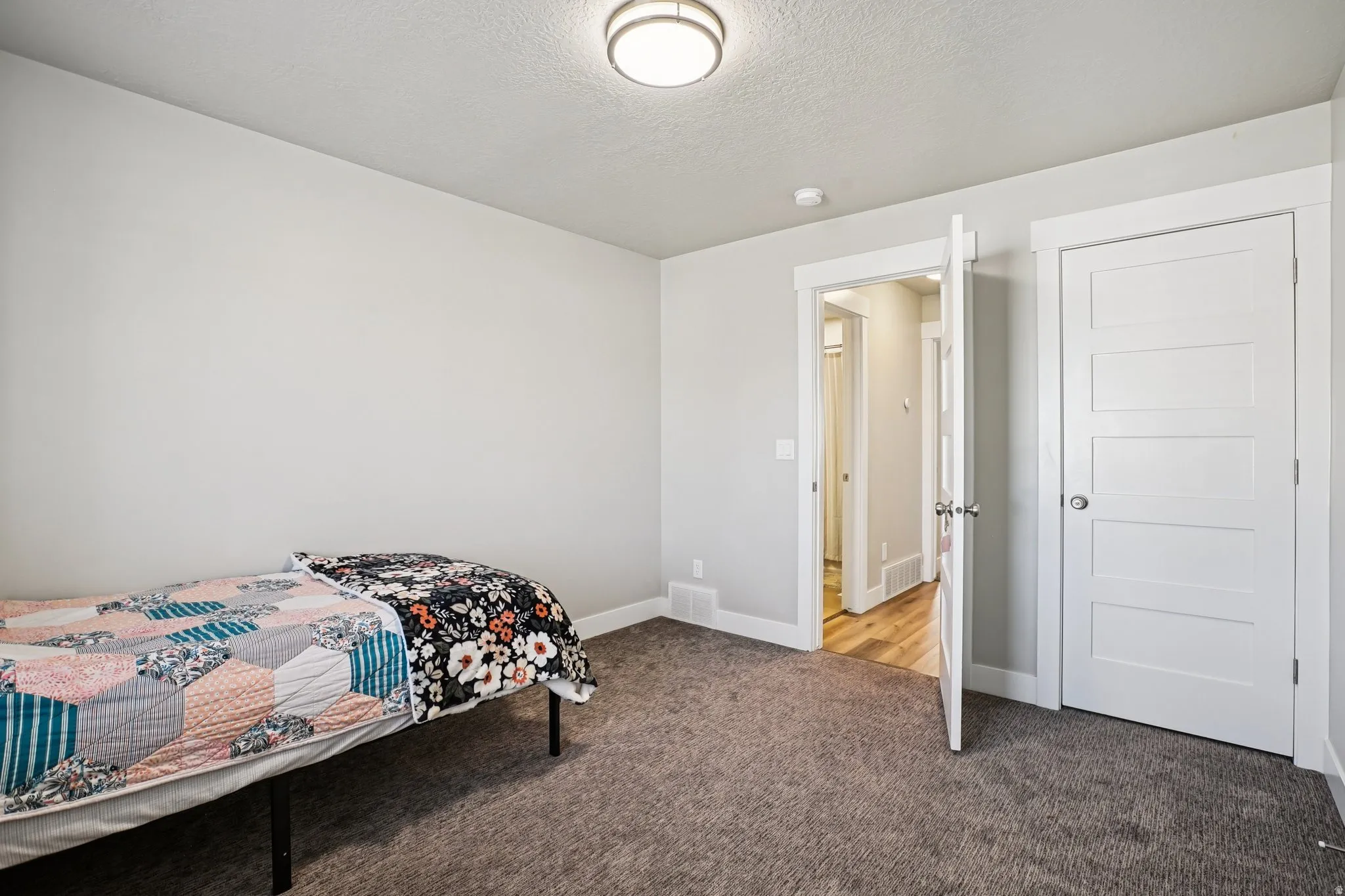 Bedroom featuring light carpet and a textured ceiling