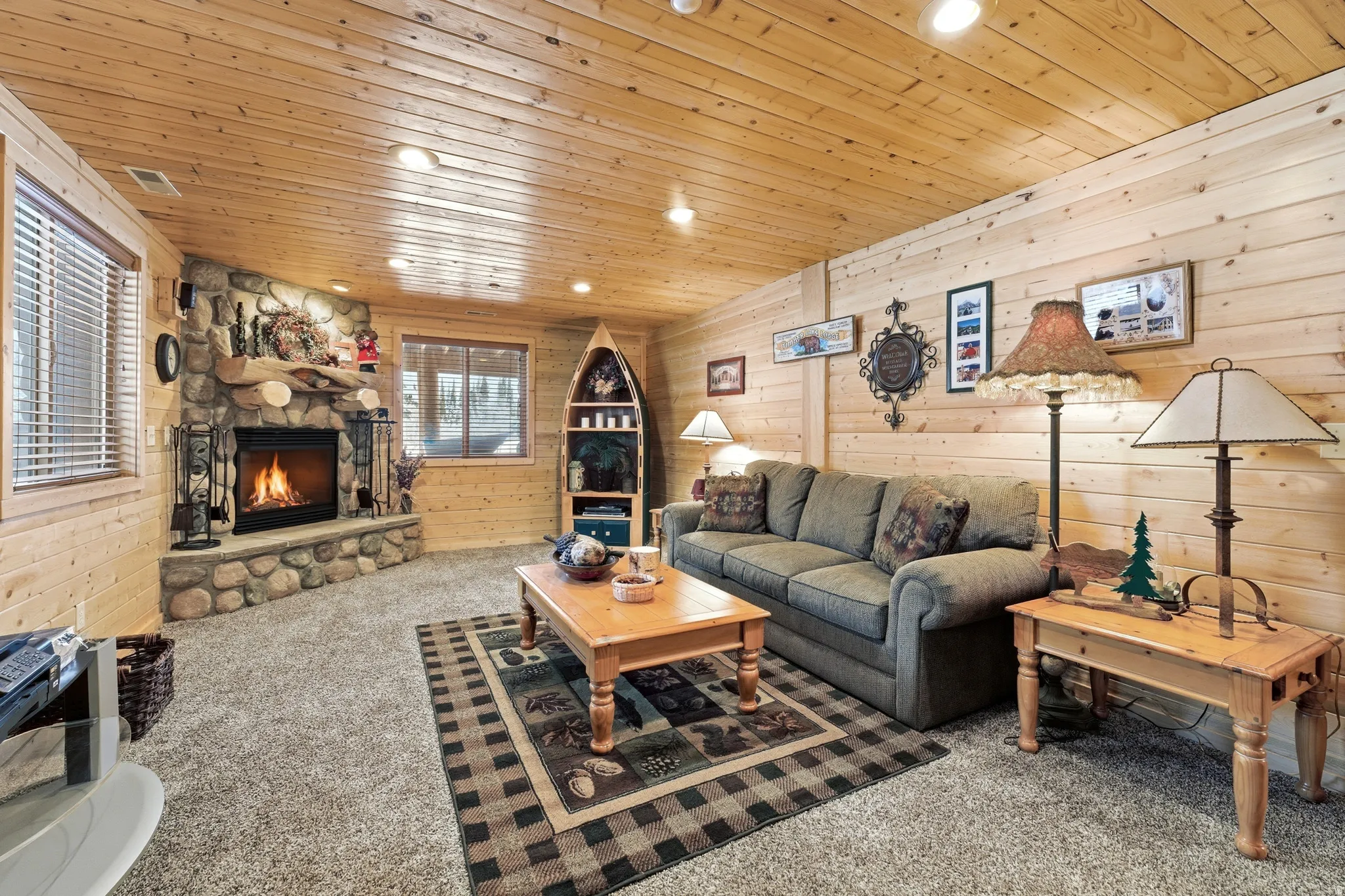 Living area with wood walls, recessed lighting, carpet floors, a stone fireplace, and wooden ceiling
