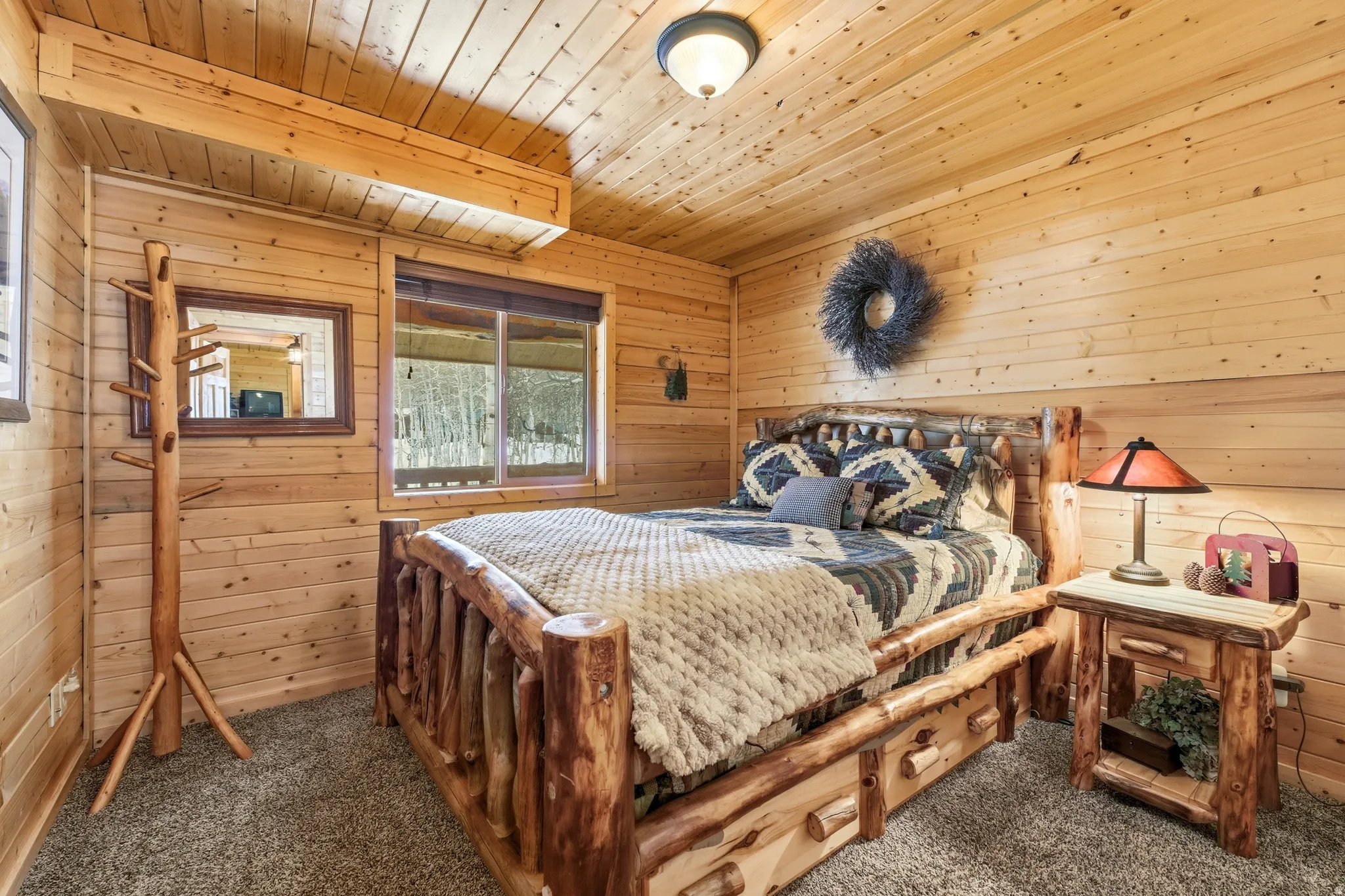 Bedroom with wooden walls, wood ceiling, and dark carpet