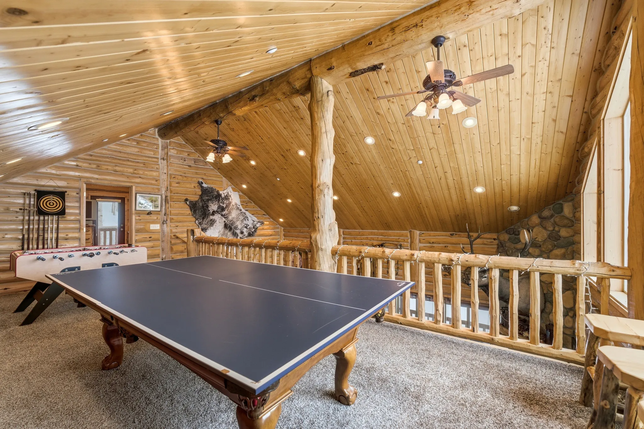 Game room with rustic walls, carpet floors, ceiling fan, recessed lighting, and a wood ceiling with exposed beams