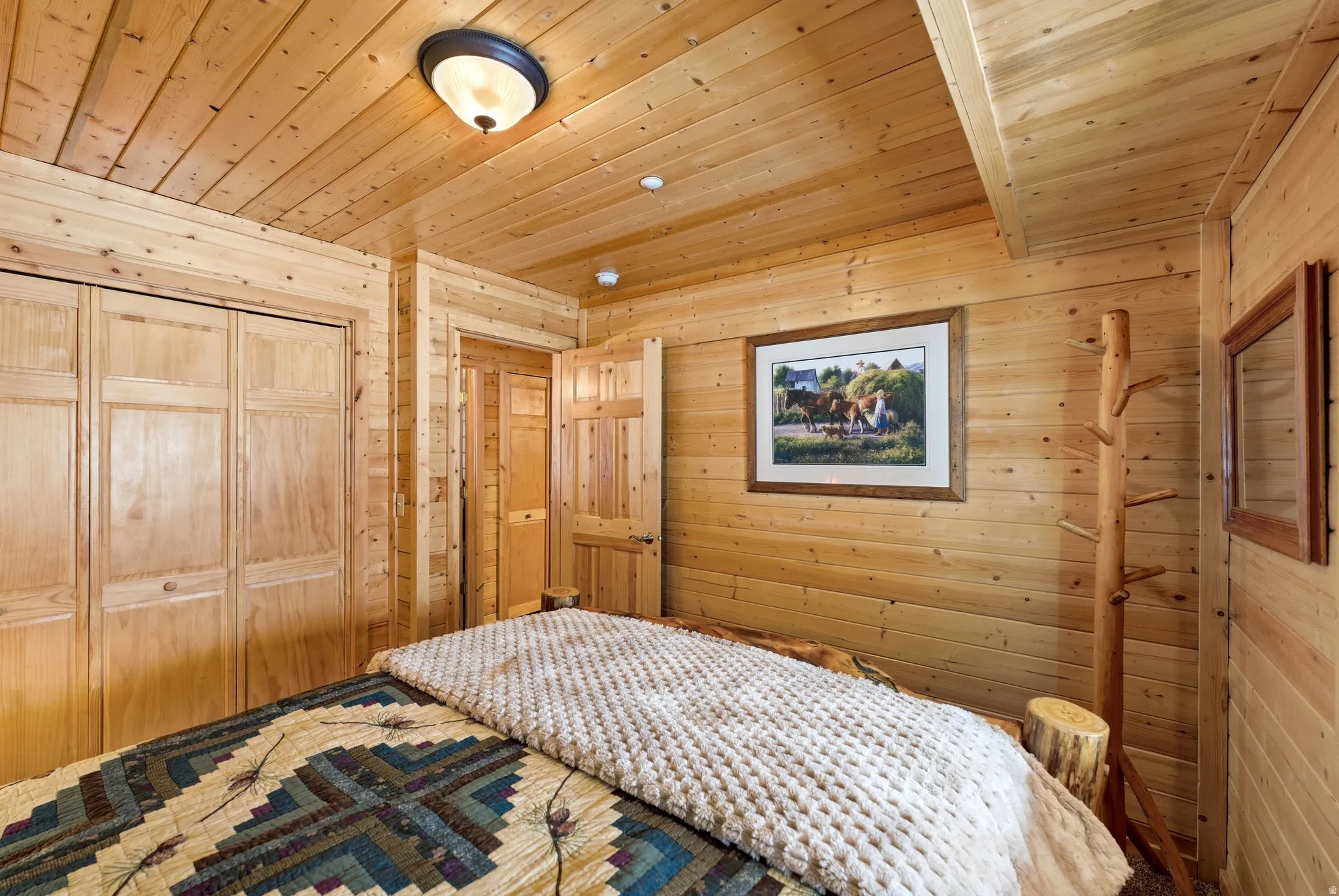 Bedroom with wooden walls, wood ceiling, and a closet