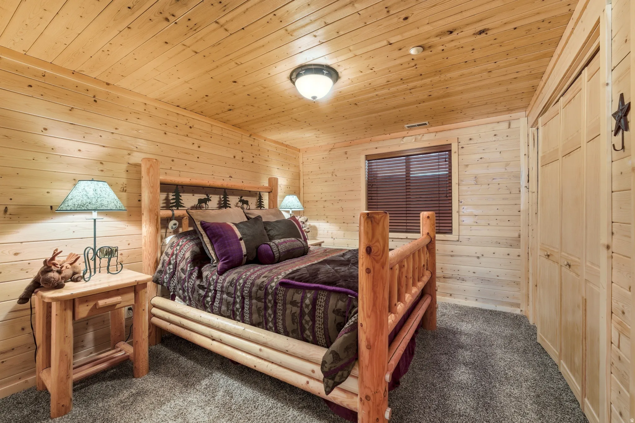 Bedroom with wood walls, dark colored carpet, a closet, and wooden ceiling