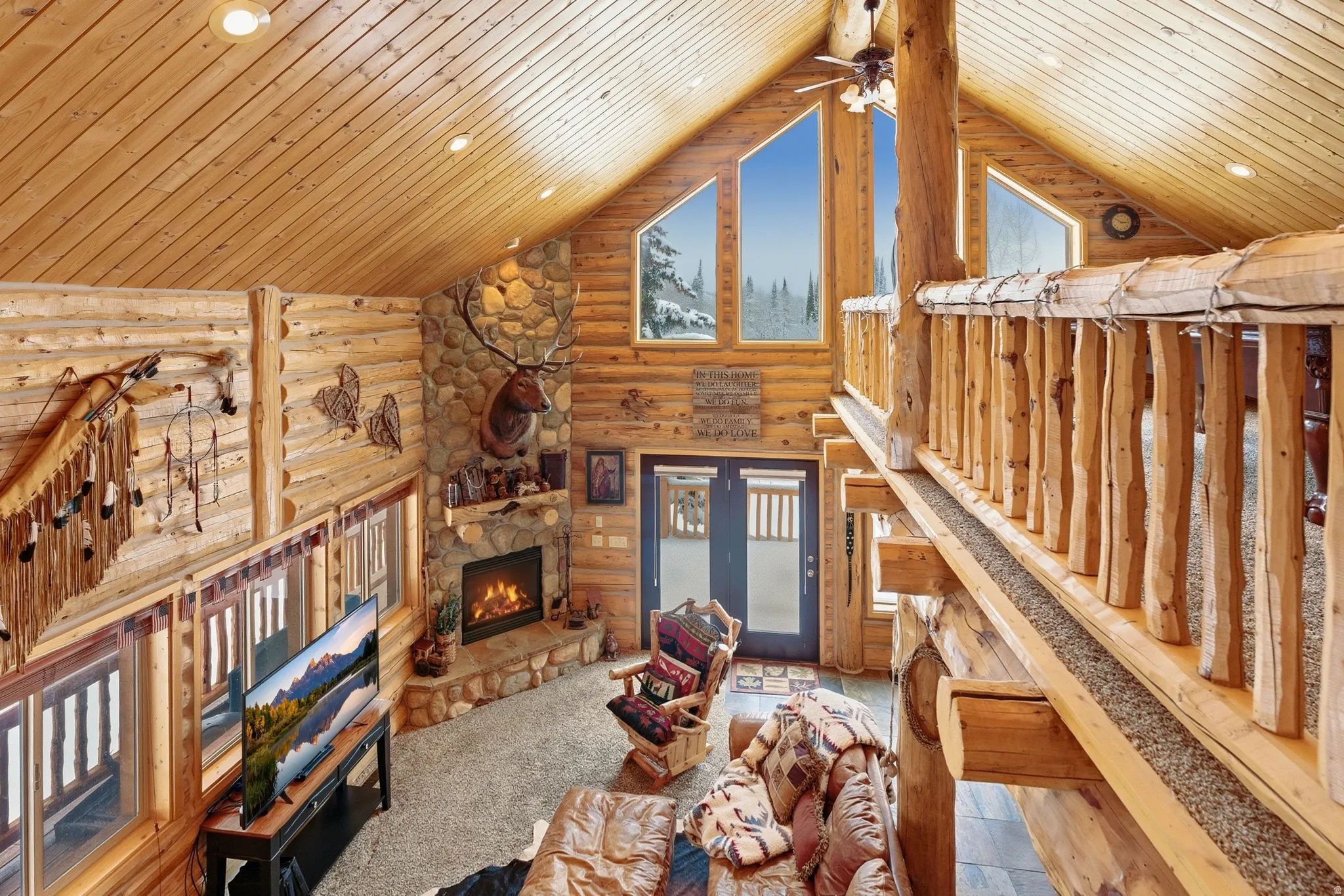 Unfurnished living room with rustic walls, a stone fireplace, ceiling fan, a high ceiling, and recessed lighting