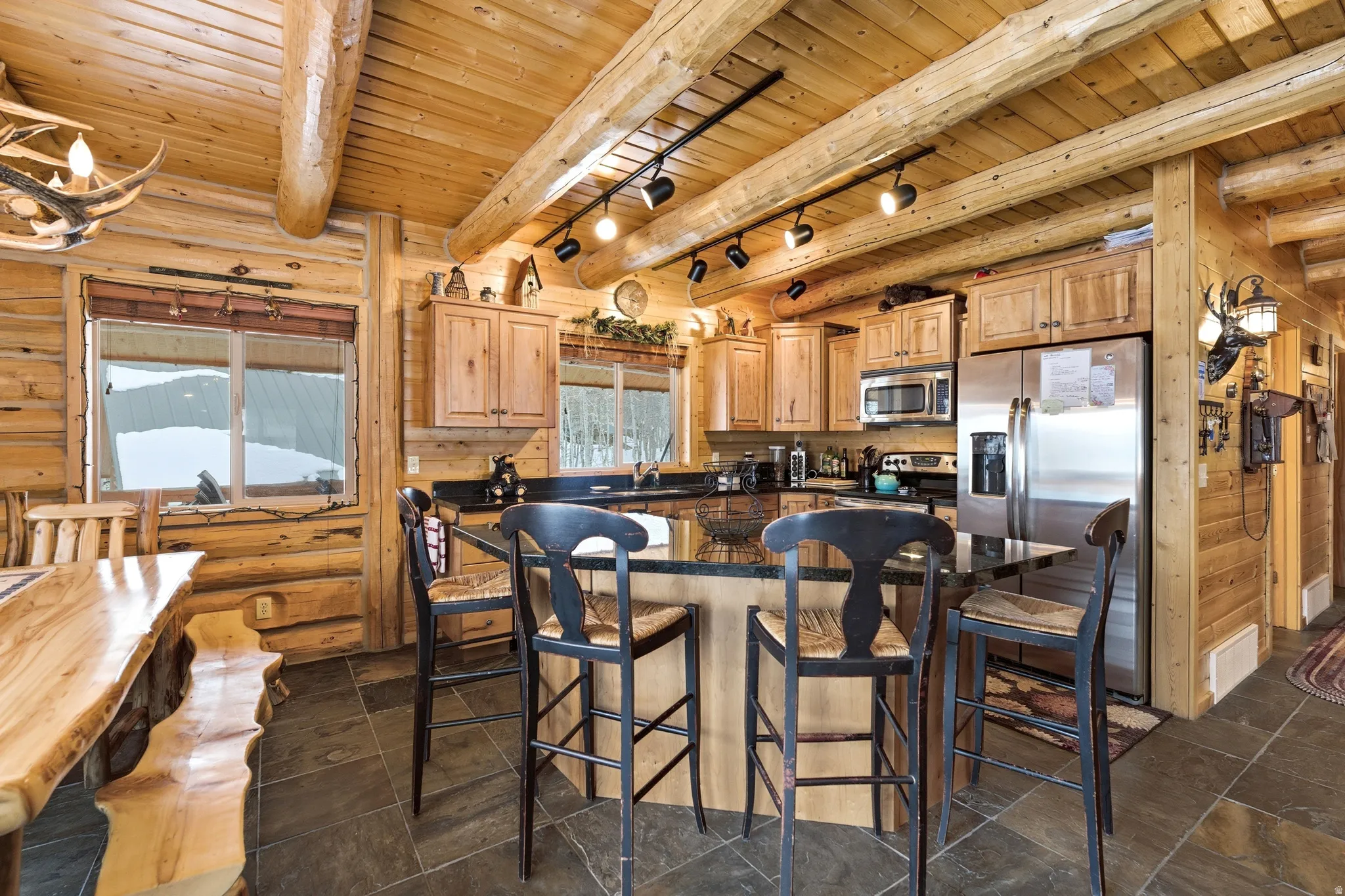 Kitchen featuring stainless steel appliances, a wood ceiling with exposed beams, a kitchen bar, a center island, and rail lighting