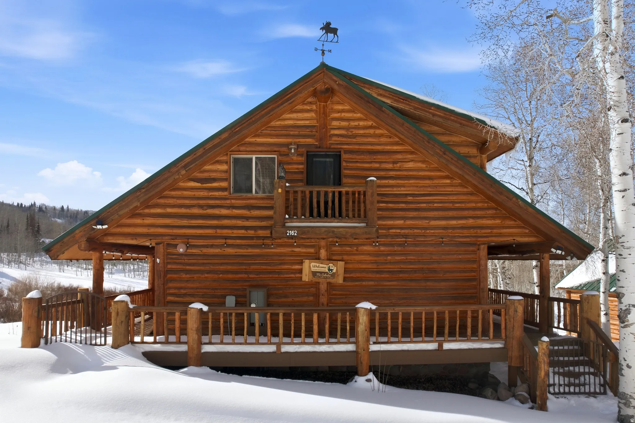 Snow covered rear of property featuring a deck and log exterior