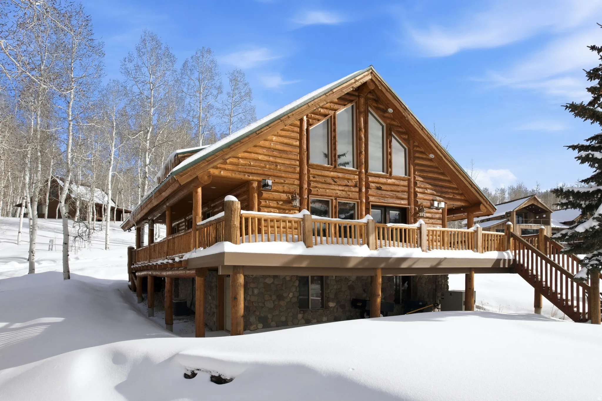 Back of property featuring log siding, stone siding, and a deck