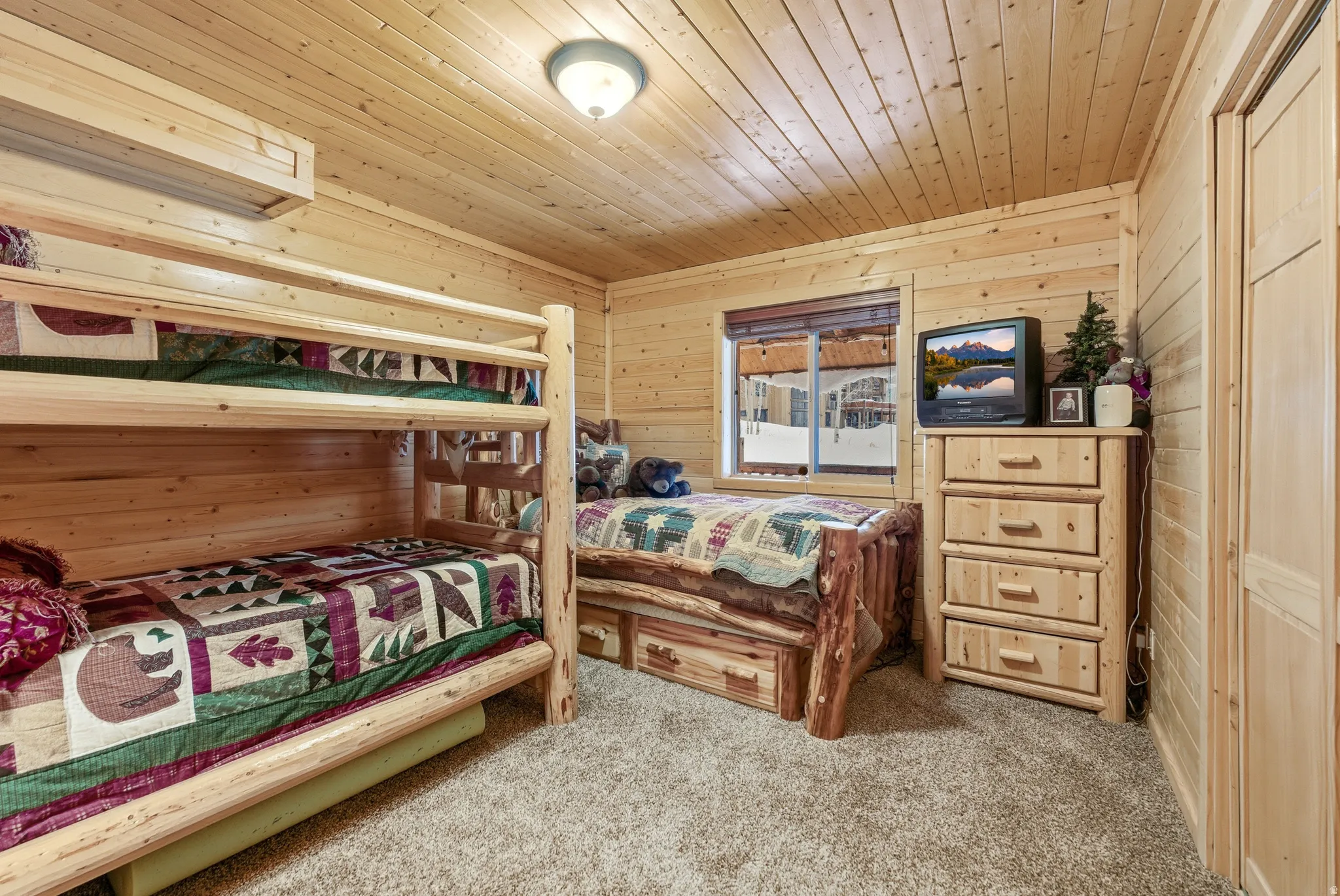 Bedroom featuring wooden walls, wooden ceiling, and light carpet