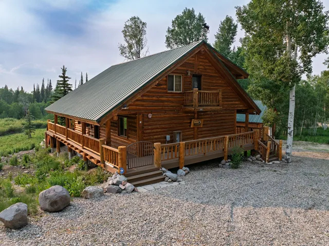 Log cabin exterior featuring a metal roof, expansive wrap-around deck, and a second-story balcony