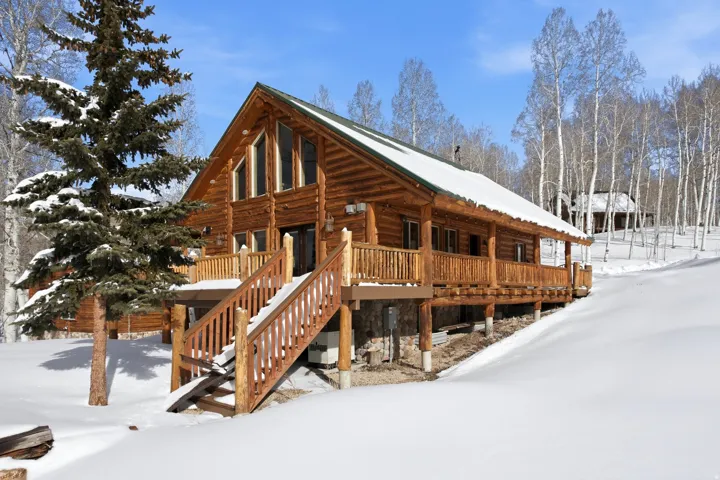 View of snow covered exterior with a porch and stairs