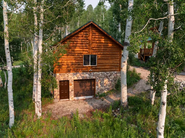 Cabin-style structure featuring log siding and a stone foundation