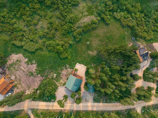 Aerial perspective showcasing a property surrounded by extensive natural landscaping, mature trees, and a dirt road