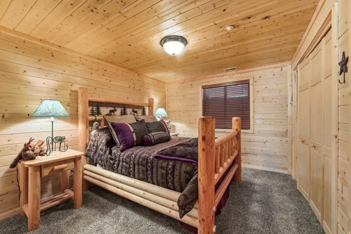 Bedroom with wood walls, dark colored carpet, a closet, and wooden ceiling