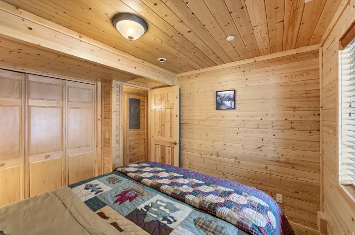 Bedroom with wood walls, wooden ceiling, and a closet