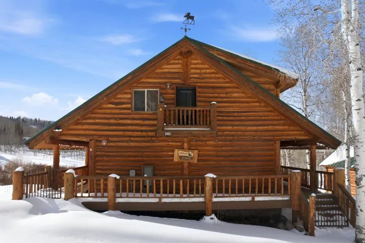 Snow covered rear of property featuring a deck and log exterior