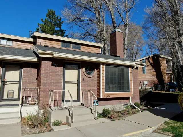 View of front facade featuring brick siding, a chimney, and roof with shingles