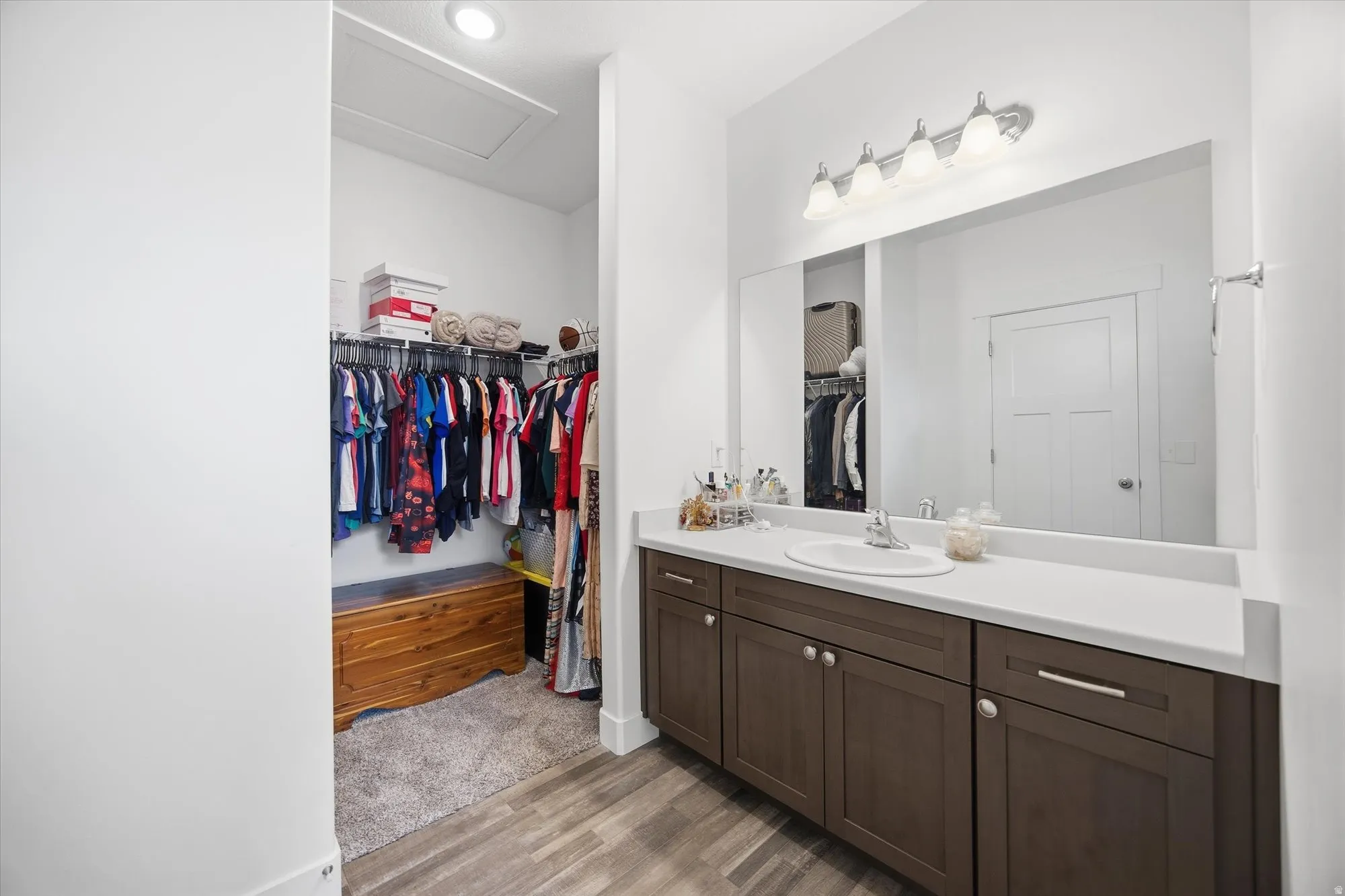 Full bath featuring vanity, a spacious closet, and light wood-style floors