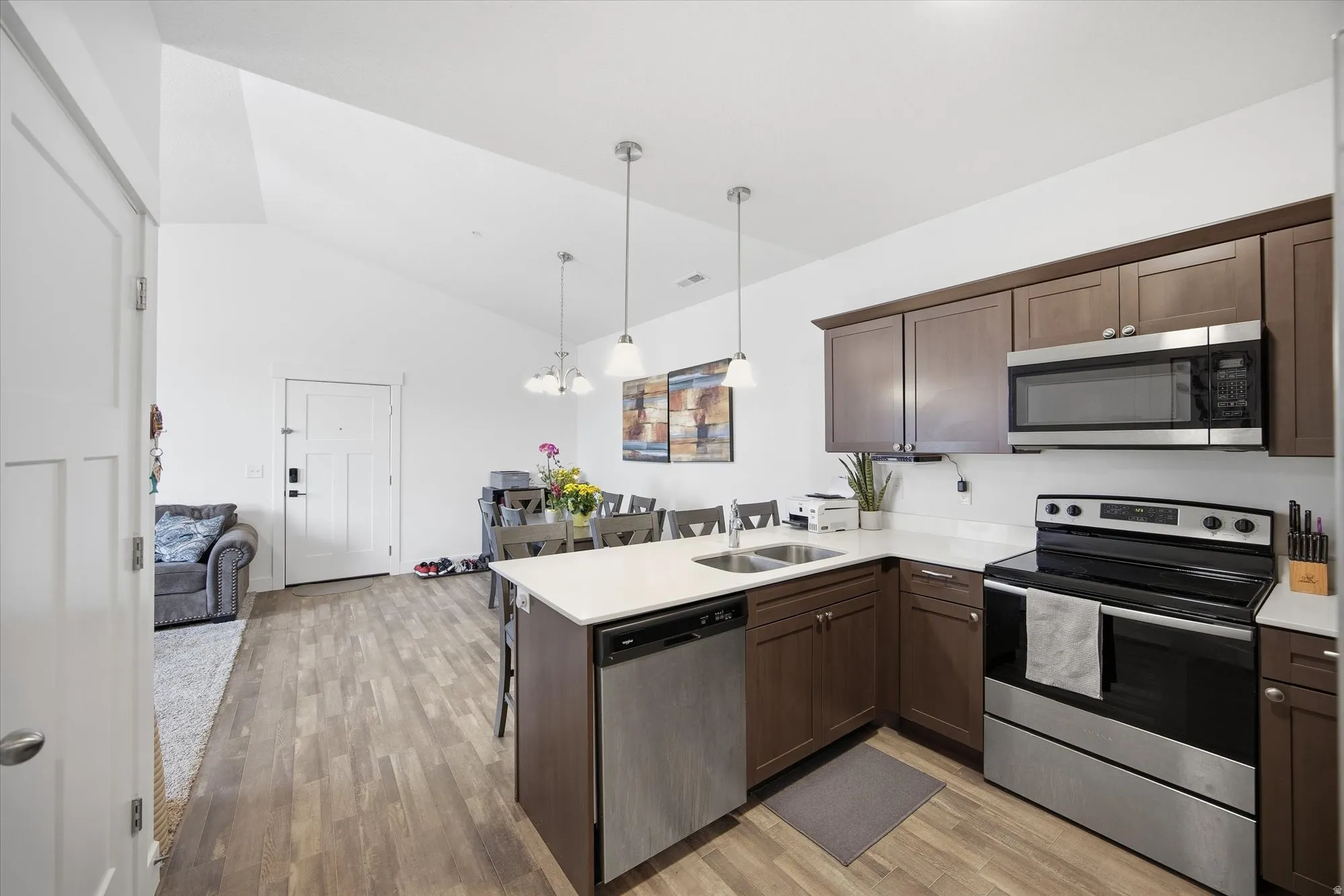 Kitchen with a kitchen breakfast bar, stainless steel appliances, a peninsula, dark wood finish cabinets, and light wood-style flooring