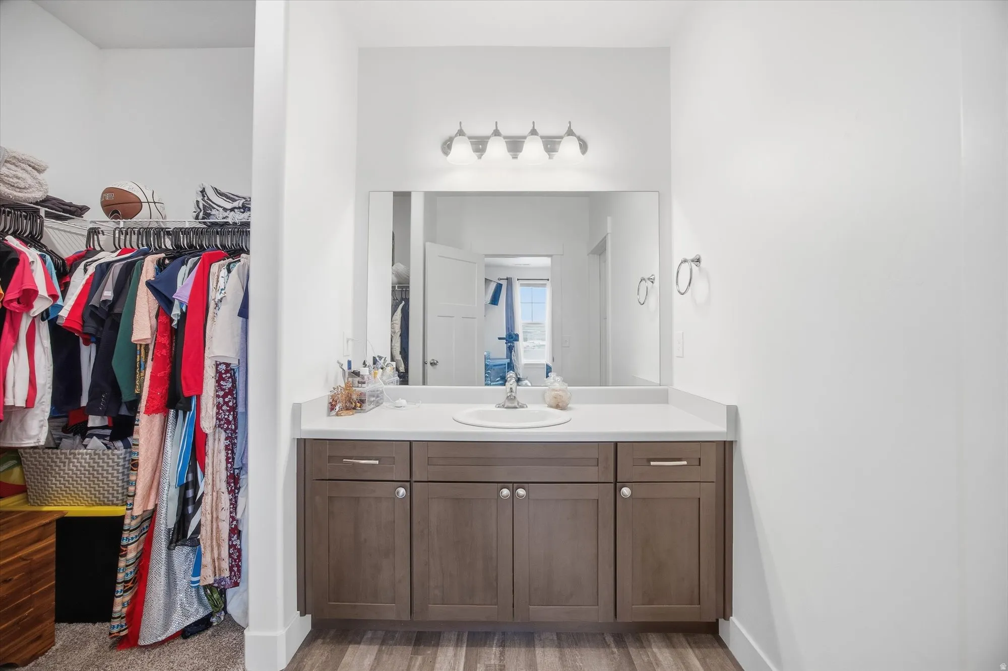 Bathroom with vanity, light wood-style flooring, and a spacious closet