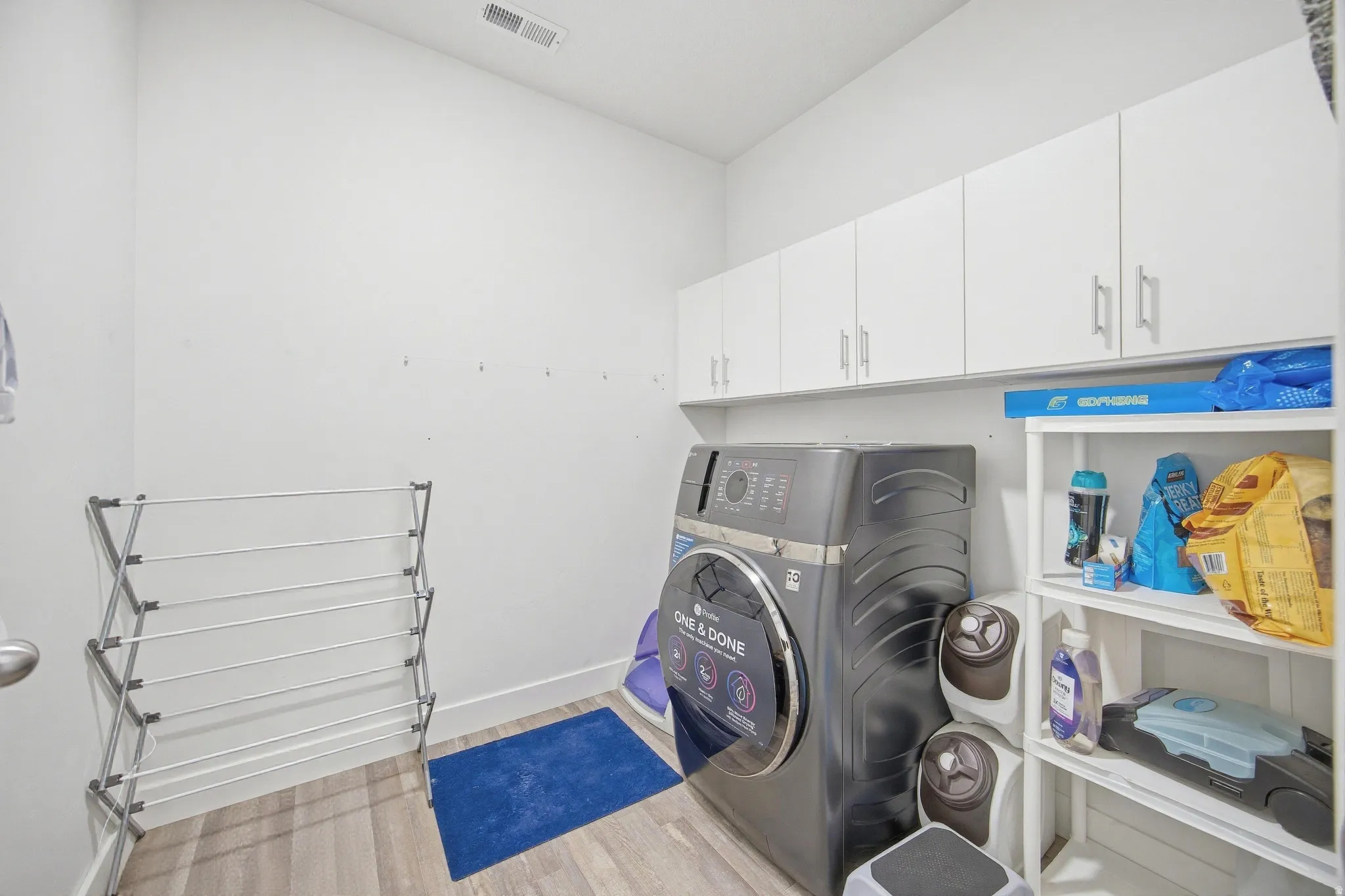 Laundry room featuring washer / clothes dryer, light wood-type flooring, and cabinet space
