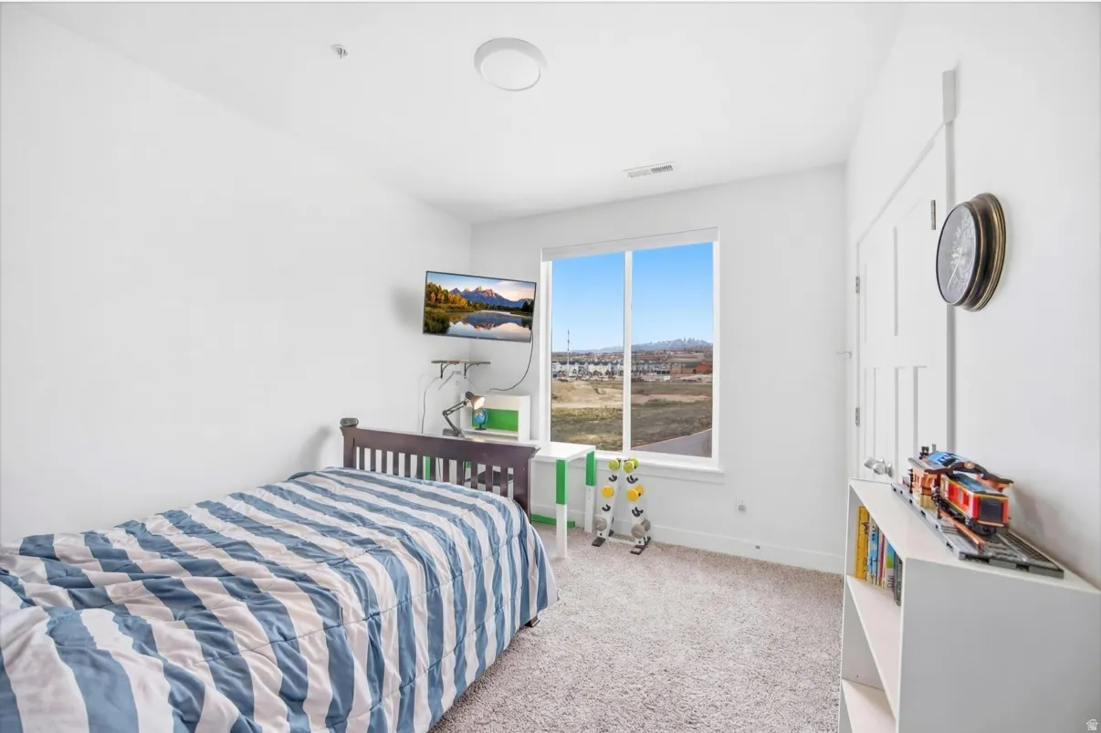Bedroom with light colored carpet and baseboards