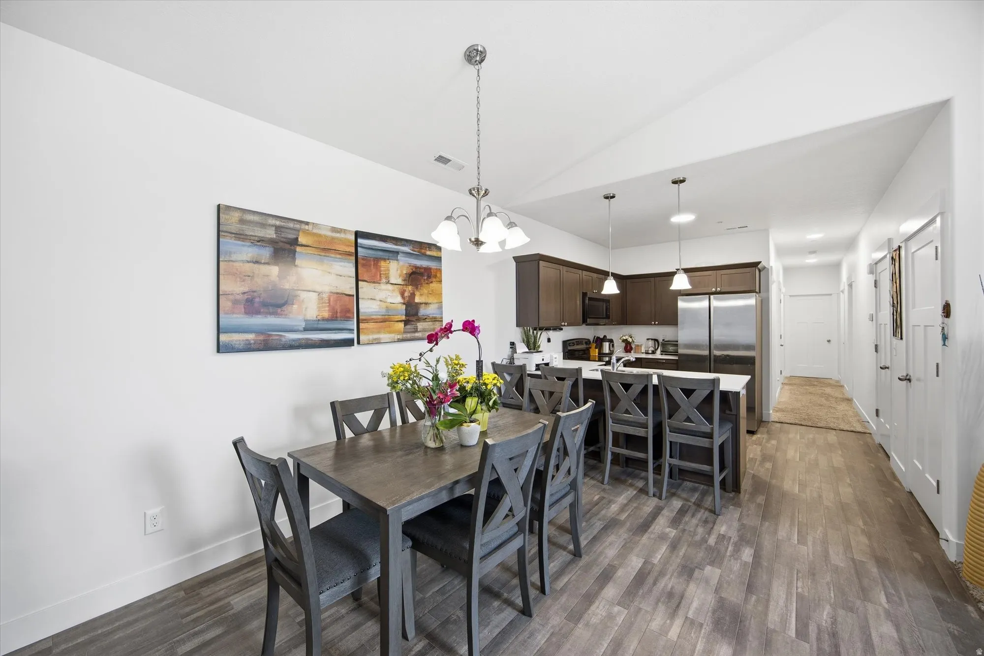 Dining space with vaulted ceiling, dark wood-type flooring, and a chandelier