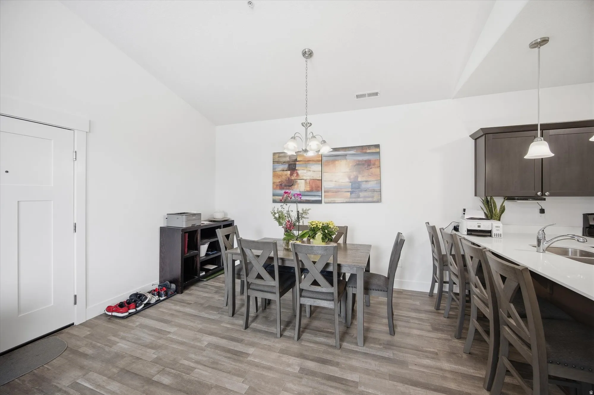 Dining room with lofted ceiling, light wood finished floors, and hanging lights