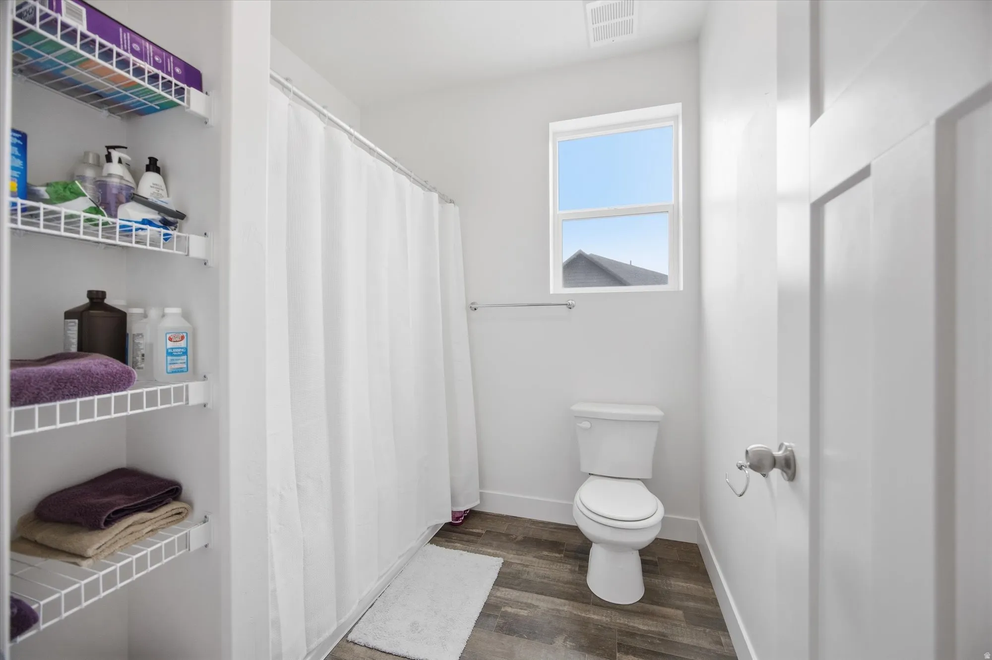 Bathroom with curtained shower and dark wood-type flooring