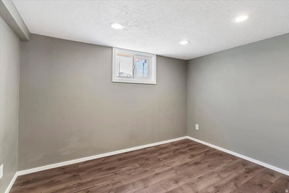 Below grade area with dark wood-style floors, a textured ceiling, and recessed lighting